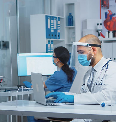 doctor-with-protection-mask-visor-typing-treatment-laptop-while-mother-comes-with-daughter